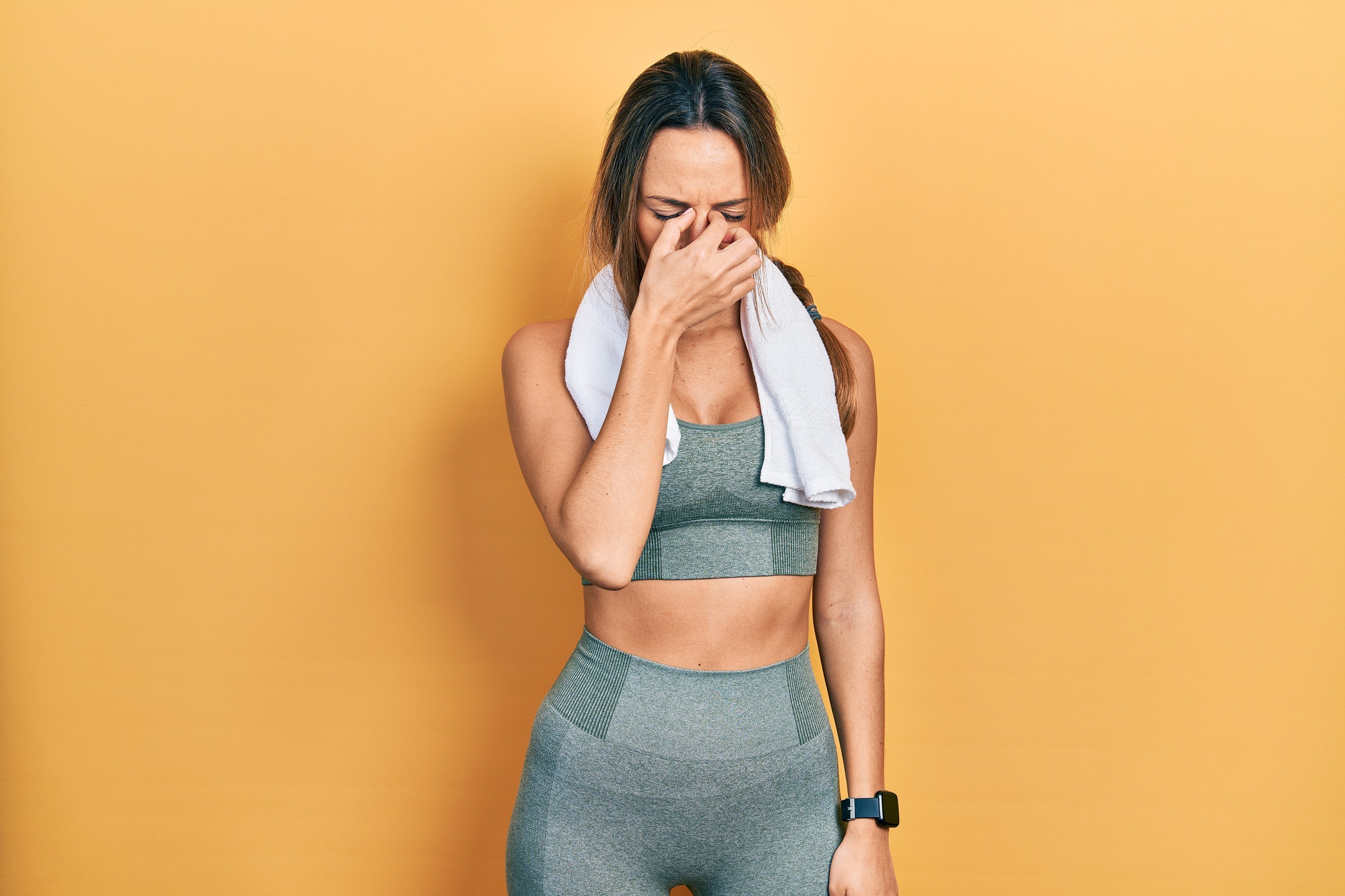 Athletic girl leaning against wall with headache